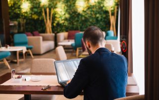 Journaliste de dos avec ordinateur dans un café